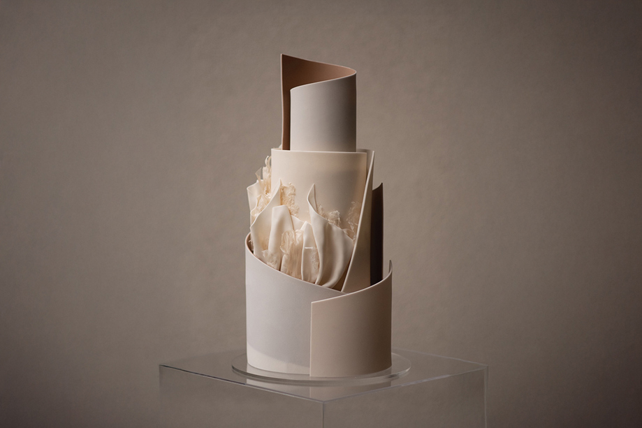 A neutral coloured, tiered cake with signature YiShi Cake ruffles